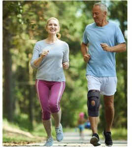 A senior couple happily jogging while wearing a knee brace.